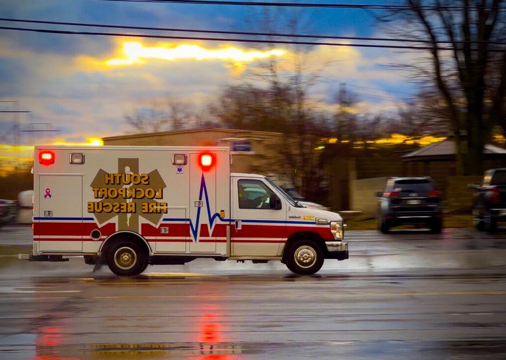救护车在行动，车灯闪烁，道路潮湿